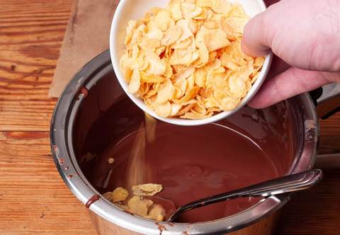 Cornflakes zur geschmolzenen Schokolade geben