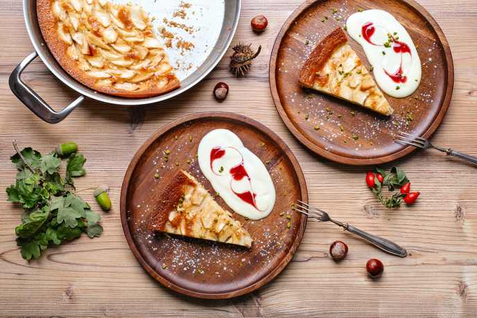 Apfelkuchen, angeschnitten auf Tellern mit Vanillesauce