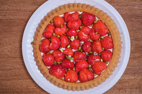 Erdbeerkuchen mit Blumen und Pistazien dekorieren