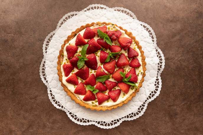 Erdbeerkuchen mit frischen Erdbeeren und Minze auf heller Cremefüllung