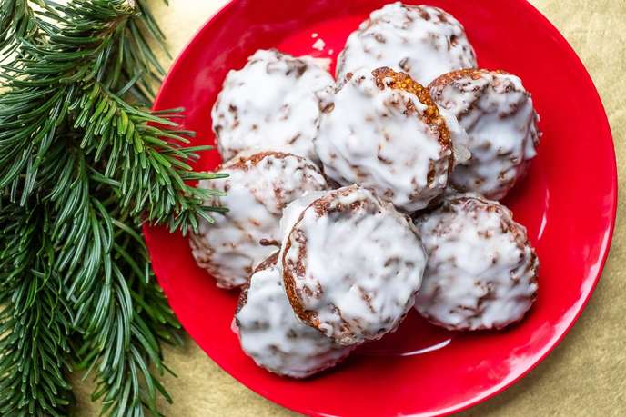Lebkuchen mit Zitronenglasur auf einem Teller auf gold Untergrund und Tannenzweige