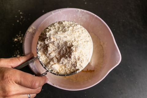 Gesiebtes Mehl wird in eine Schüssel mit weiteren Zutaten gegeben