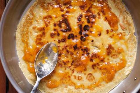 Pfannkuchen in der Pfanne mit Marmelade bestreichen