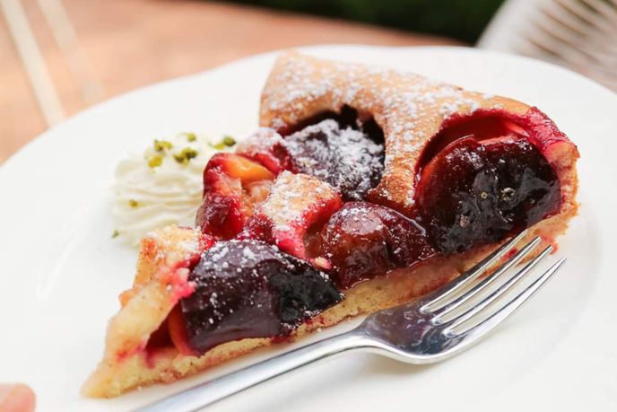 Pflaumenkuchen mit saftigen Pflaumen, Puderzucker und Schlagsahne