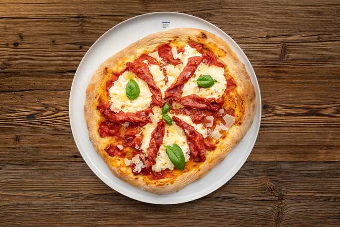 Pizza Diavola mit scharfer Salami, Mozzarella und Basilikum auf dem Teller