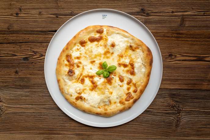 Käsepizza Quattro Formaggi mit geschmolzenem Käse und Basilikum