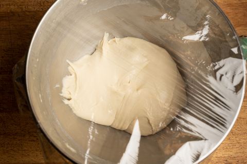 Pizzateig mit Folie zum gehen lassen abgedeckt