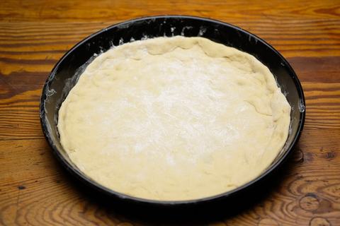 Pizzateig frisch in das Pizzablech eingelegt rund