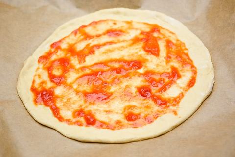 Pizzateig mit tomatensauce bestreichen
