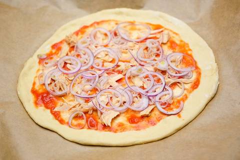 Zwiebeln, fein geschnitten auf der Thunfischpizza verteilen