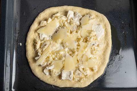 Quattro formaggi Pizza roh belegt mit vier Käse auf dem Backblech