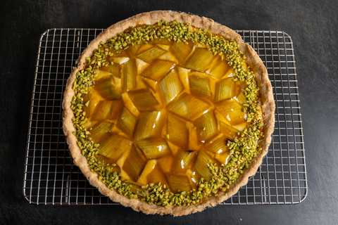 Rhabarber-Tarte mit Aprikosenglasur und Pistazienrand auf Gitter abgekühlt