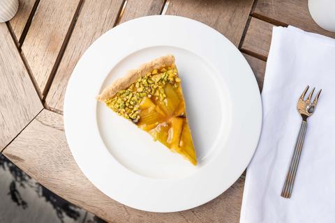 Rhabarber-Tarte-Stück mit Pistazien von oben auf weißem Teller