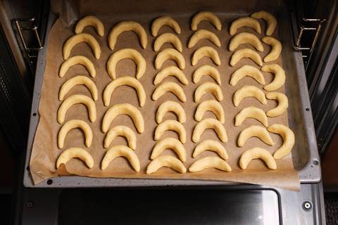 Geformte Vanillekipferl auf dem Backblech in den Ofen schieben