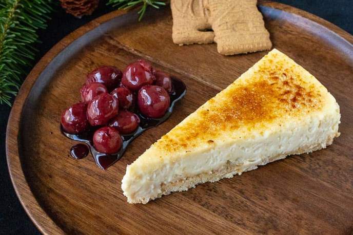 Weihnachtskuchen mit Zimtkirschen und Karamell-Kruste, angerichtet auf einem Holzteller