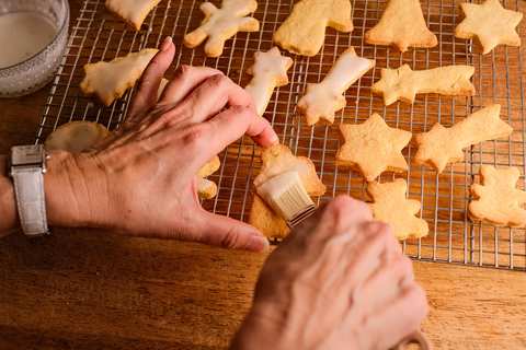 Weihnachtsplätzchen mit Zuckerglasur bestreichen