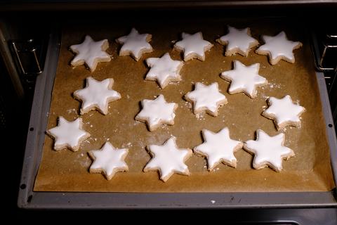 Zimtsterne mit Glasur auf Blech im Backofen